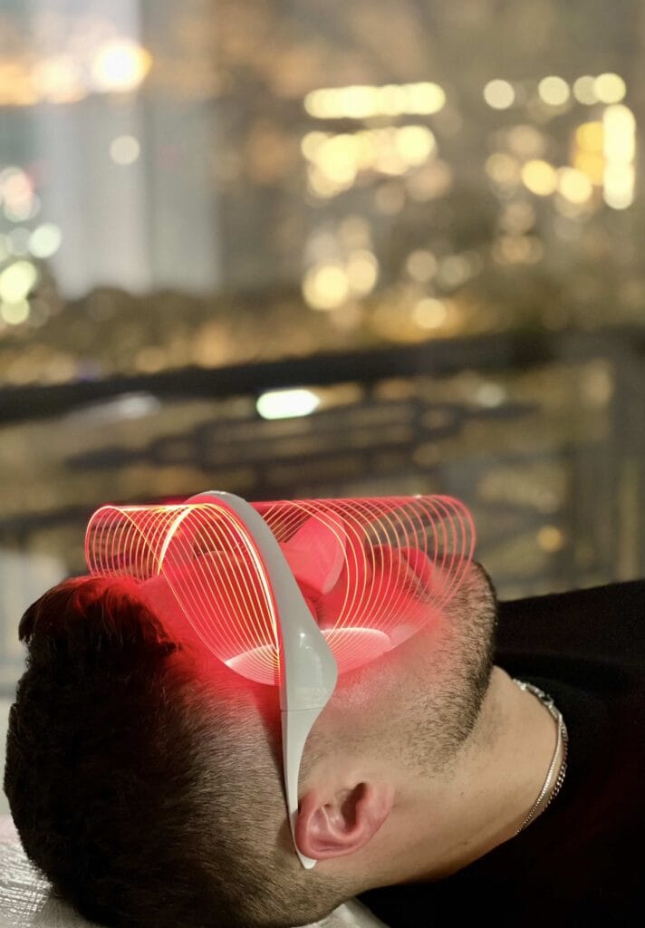 Hombre con tratamiento de limpieza facial y máscara LED de luz roja para mejorar la piel